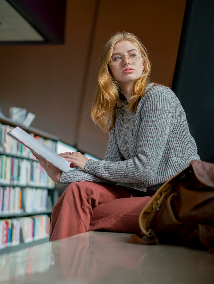 Mastering the First Impression: Your intriguing post title goes here A young woman with glasses reads attentively in a contemporary library environment.